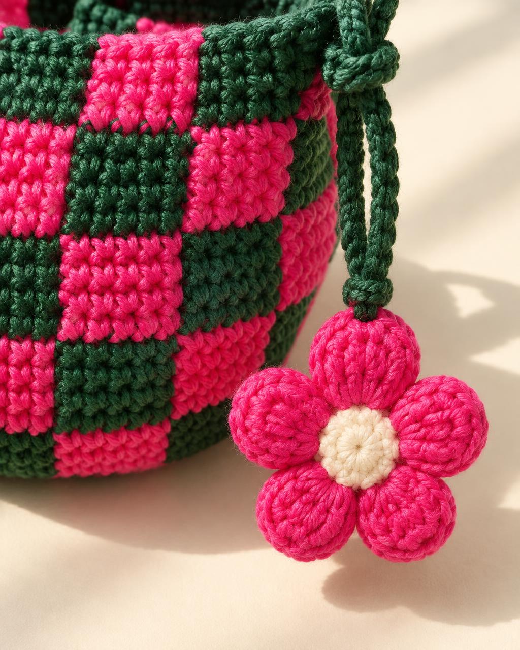 A tactile pink crochet flower against green and pink stitching